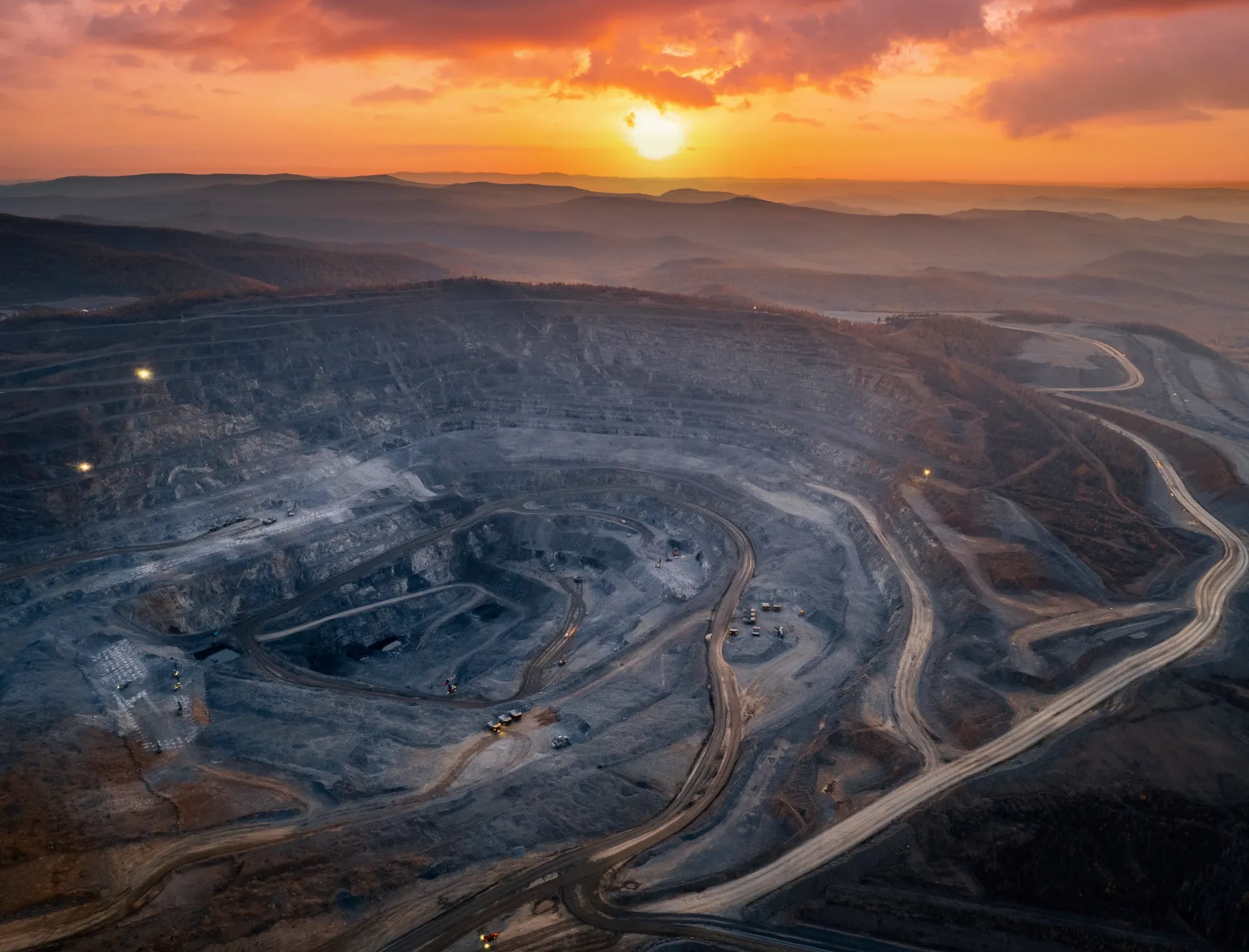 Sunset over a desert leading to a large mining field with multiple roads